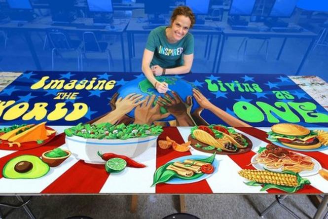 A woman smiling and painting a mural