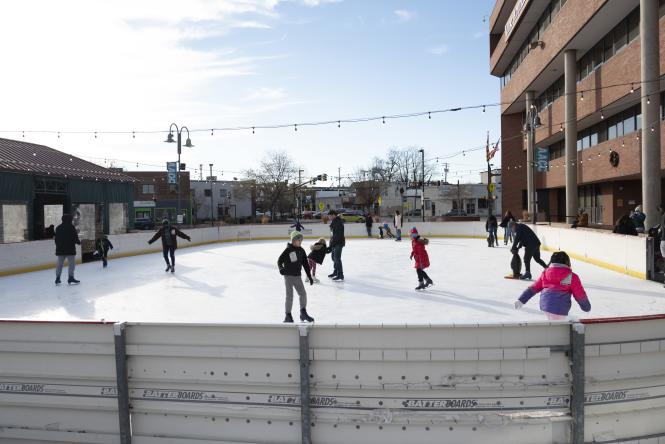 Kids and adults ice skate outdoors