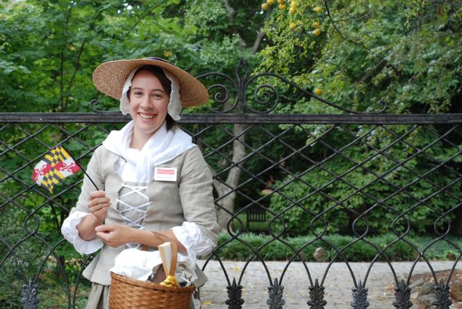 Woman in colonial dress holding the Maryland Flag