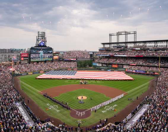 A massive flag and crowd is shown at Coors Field during the MLB All-Star Game 2021