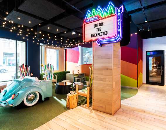 The Curtis, a DoubleTree by Hilton hotel, lobby with a car and neon sign in Denver, Colorado.