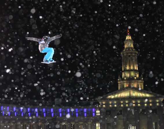 A snowboarder flies through the air amid flurries in front of the Colorado Capitol