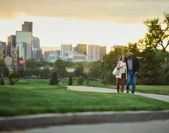 A couple walks along a paved path in a Denver park before their trip on Canyon Spirit