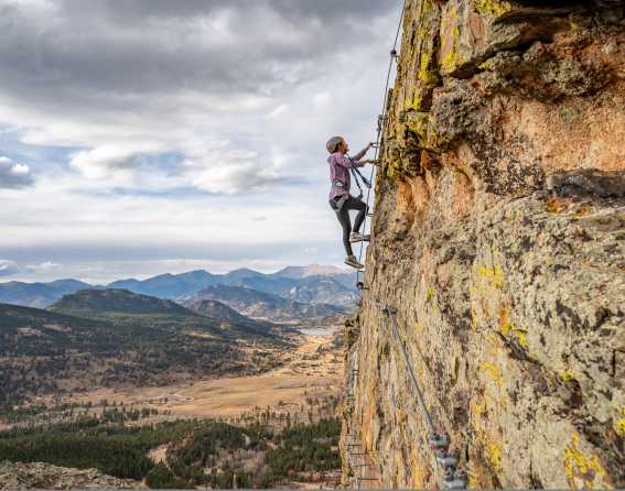 A person climbing a ladder on a high rock wall at Estes Park, Colorado.