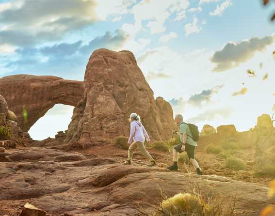 A couple walks up to an arch in Arches National Park, Moab on the Canyon Spirit journey