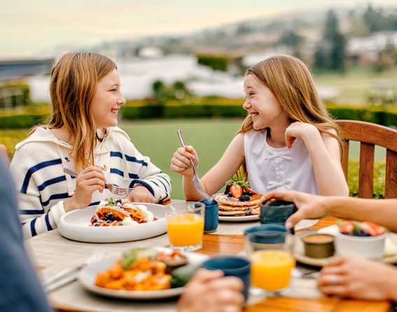 Two young girls having a summer breakfast on the patio at the Omni Interlocken Resort & Spa.