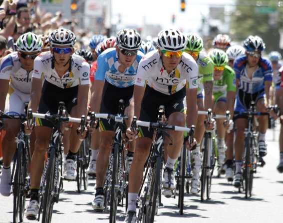 Bikers are racing along a paved street in Denver during the USA Pro Cycling Challenge