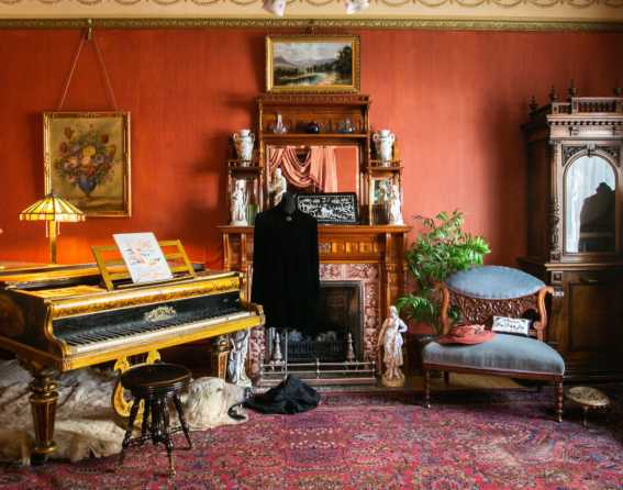 A piano, love seat and fireplace is visible in the living room at the Molly Brown House Museum