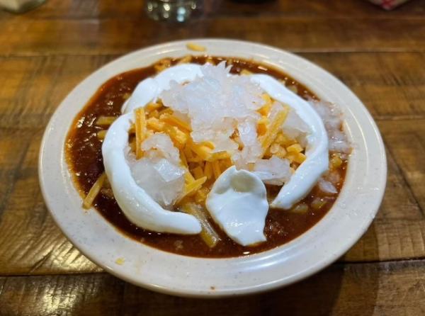 Bowl of chili with cheese, raw onion, and sour cream