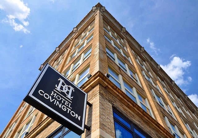 Hotel Covington with its sign and a bright blue sky behind its tan brick exterior