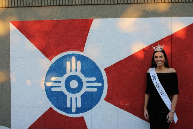 Miss Kansas poses next to a mural of the Wichita flag in the Douglas Design District