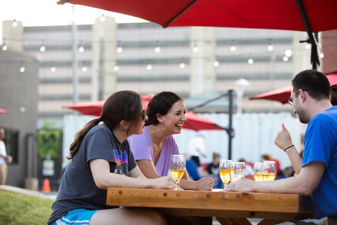 A group of friends share brews and laughs at a picnic table on Nortons Brewing Company's patio in Wichita