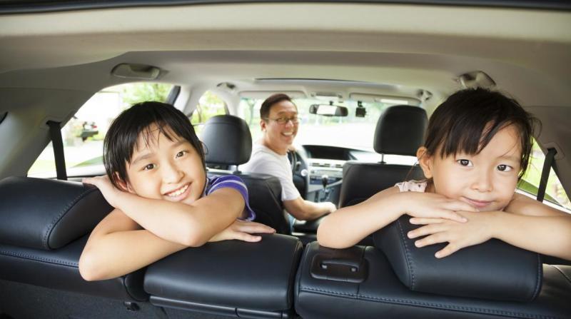 A family smiles from inside a minivan
