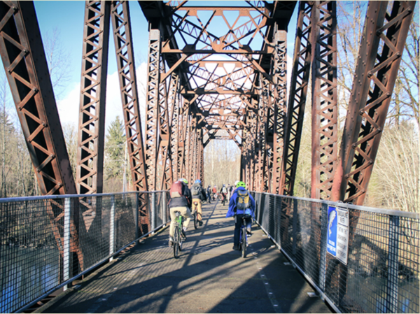 A photo of a metal bridge with bikers and pedestrians