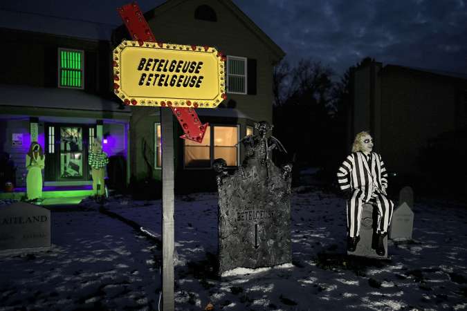 Halloween Lights Tour Home Decor: A home is decorated with a "Betelgeuse" sign and figures from the movie Beetlejuice. A fake Beetlejuice character is visible in the background.