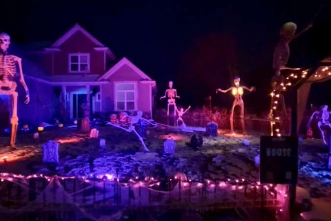 A graveyard of skeletons is illuminated by lights for Halloween in the front yard of a home