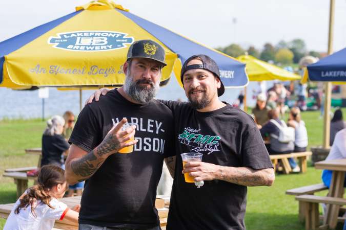 two men smiling, holding beers.