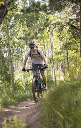 man mountain biking through the trees
