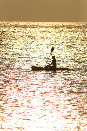 Silhouette of a single kayaker at sunset