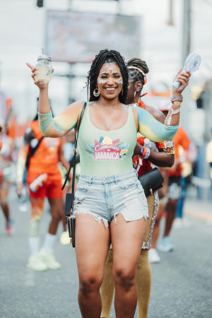 Woman at Carnival Road March 2023 holding a drink and a portable fan