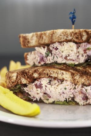 Chicken sandwich stacked high with a pickle on the side