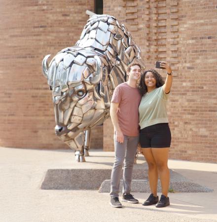 Couple Posing in Front of Buffalo Sculpture