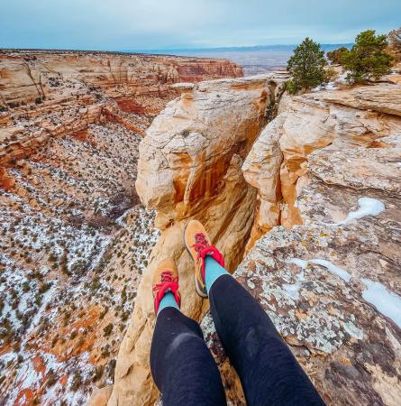 Person's feet over edge on Colorado National Monument with snow