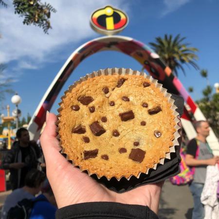 Image a cookie from Jack-Jack Cookie Num Nums being held in front of Incredicoast sign at Disney California Adventure