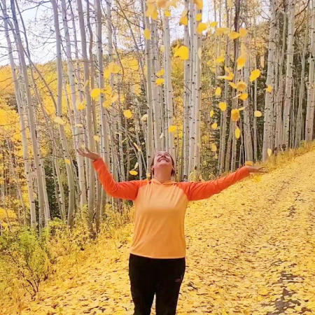 Woman tossing leaves in the air surrounded by Fall colors