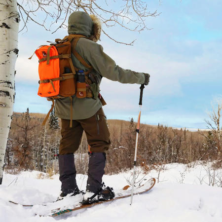 Man on Skis Overlooking Forest with Hill People Gear