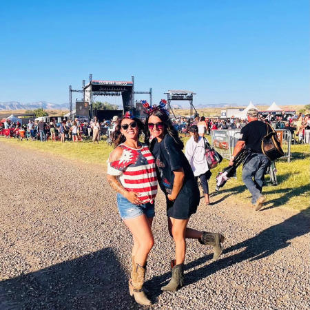 Two women posing in front of Country Jam's Stage