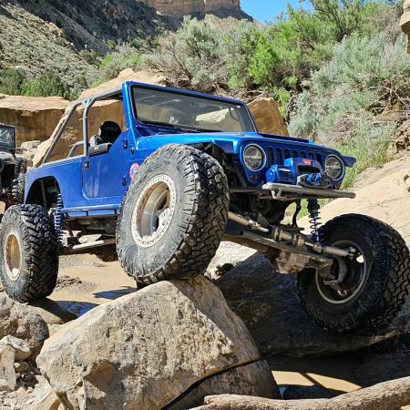 Blue Jeep Crawling Over a Large Rock