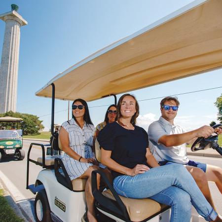 Visitors riding a golf cart near Perry’s Victory and International Peace Memorial