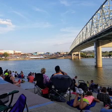 People sitting on serpentine wall in Cincinnati with the Ohio river and a bridge behind them
