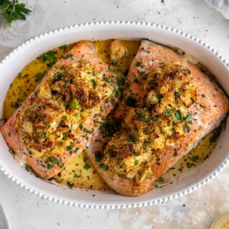 Salmon topped with a crab bake in a white dish on a table
