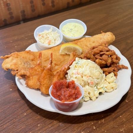 Fried seafood platter with fish, calamari, shrimp, and macaroni salad on a white plate at Tucci’s Family Diner.