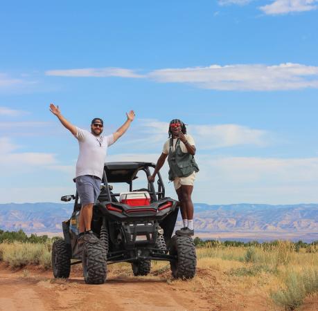 Two men hanging off an ATV