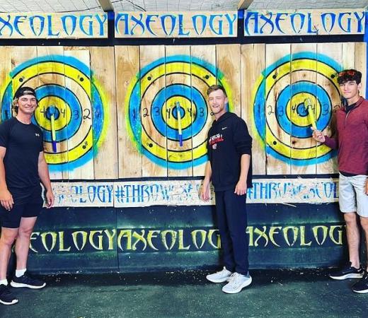 Three Males Standing in front of Bulls Eyes at Axeology