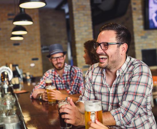 People Laughing at a Restaurant Bar with Beers