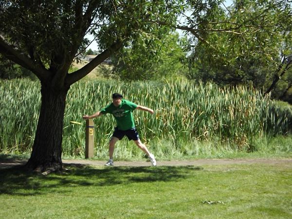 A mad tees off with his flying disc at a disc golf course