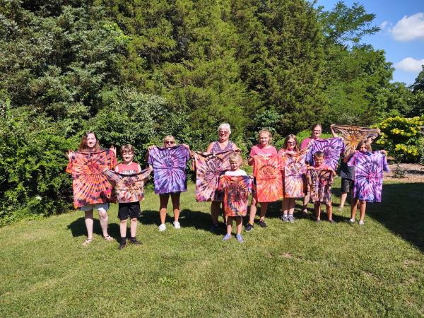 Group of adults and children displaying colorful tie dye shirts after an outdoor activity in Southern Indiana.
