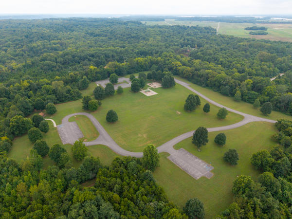 Aerial view of open green recreation areas, winding roads and parking lots surrounded by dense forest at Charlestown State Park.