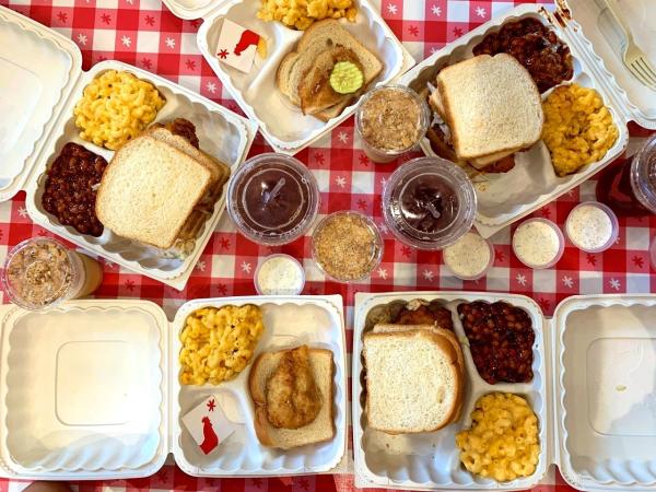 View from above of spread of various boxed meals of chicken wings, toast and mac & cheese at Hot Chicken Takeover