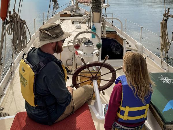 A child and adult sailing on a sailboat