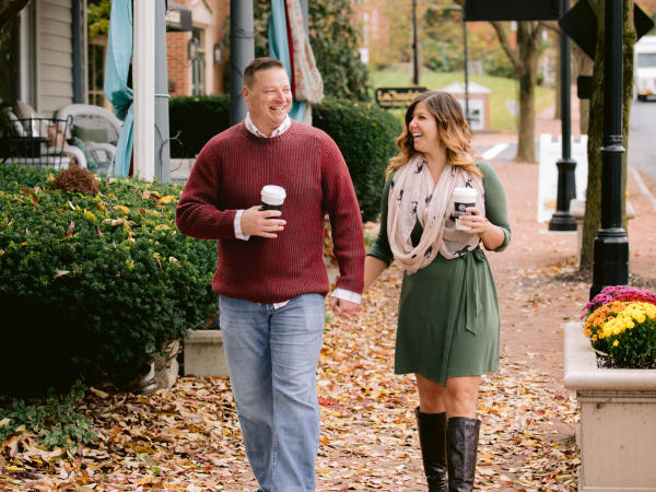 A couple walking hand in hand with coffee cups through the leaf covered, bricked lined streets of Historic Dublin in the fall.