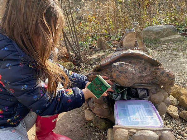 Little girl discovering a Riverbox shaped like a turtle and stamping her passport
