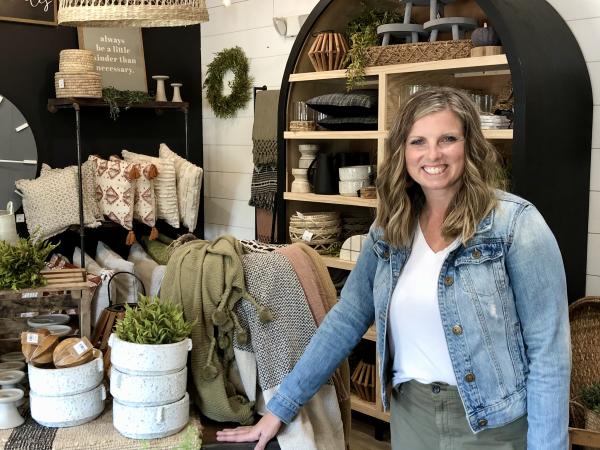 Chelsea Gorsuch posing with country and primitive decor inside her shop