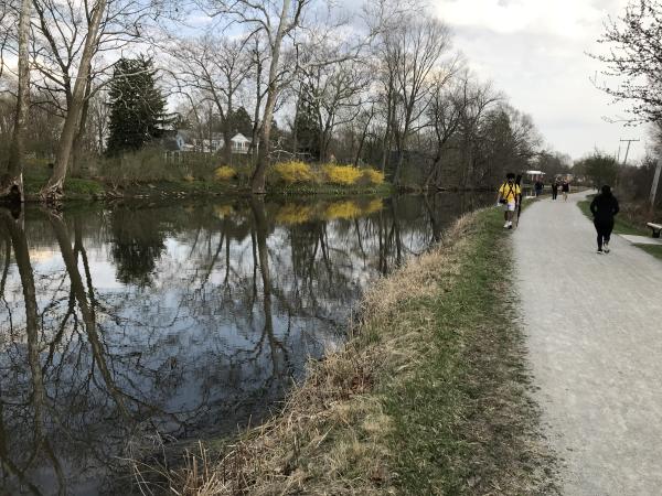 People walk on a trail along the former canal in Goshen, Indiana on a cloudy day