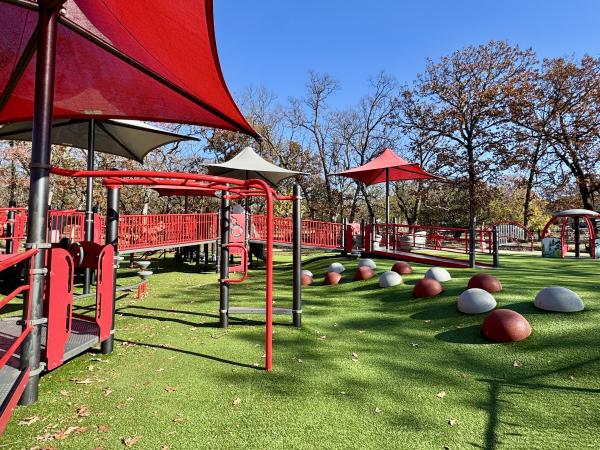 A red and white playground spans across green turf at Creekmore Park, Fort Smith, Arkansas..