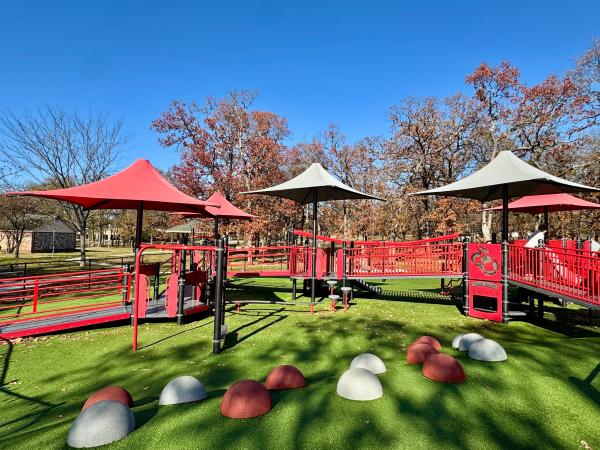 The red Creekmore playground structures contrast the technicolor green turf on a sunny Fall afternoon in Fort Smith, Arkansas.